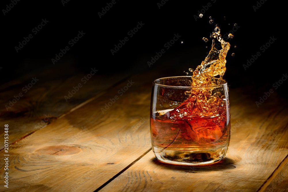 Whiskey splash in glass on a wooden table.